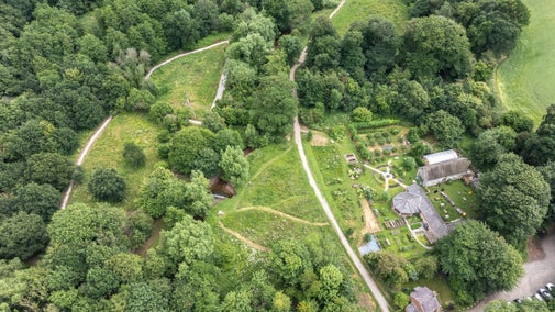 An aerial view of the Mindful Meadow and Mindful Garden at Erddig, Wrexham, with winding paths, trees, and the buildings and nature garden at Felin Pulston